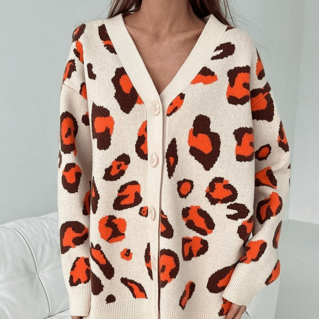 Frau trägt beige Strickjacke mit auffälligem Leopardenmuster in Orange und Braun, modisches Design, Herbstmode, gemütlicher Stil.