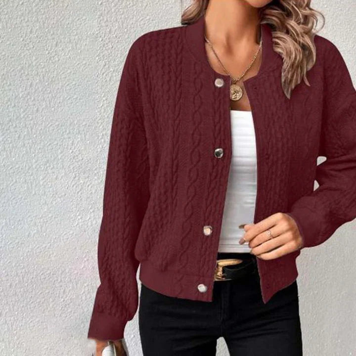 Frau trägt bordeauxrote Strickjacke mit Zopfmuster, weißem Top und schwarzer Hose. Modetrend, Damenmode, Herbstoutfit, stilvolle Kleidung.
