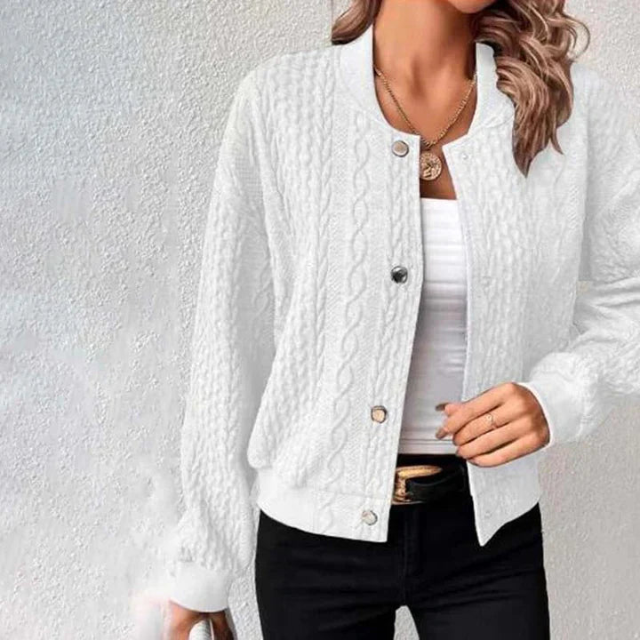 Frau trägt weiße Strickjacke mit Zopfmuster, kombiniert mit weißem Top und schwarzer Hose. Modetrend, Damenmode, stilvolle Freizeitkleidung.