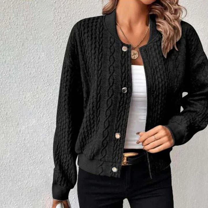 Schwarze Strickjacke mit Zopfmuster, getragen von einer Frau mit weißem Top und Jeans. Modische Damenbekleidung, Herbstmode, lässiger Stil.
