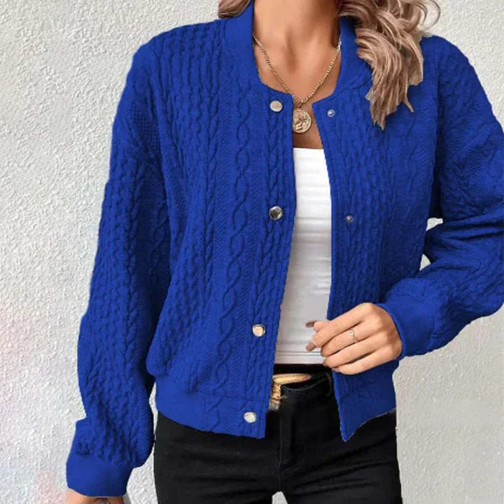Frau trägt blaue Strickjacke mit Zopfmuster, weiße Bluse und schwarze Hose. Modetrend, Damenmode, stilvolle Freizeitkleidung.