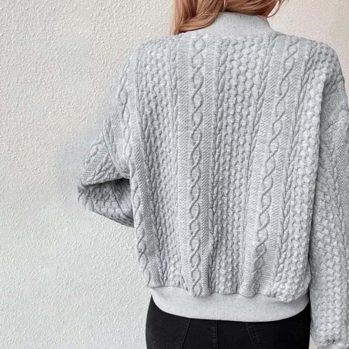 Frau in grauem Strickpullover mit Zopfmuster, Rückansicht. Modischer Winterpullover, gemütlich und stilvoll. Perfekt für kalte Tage.