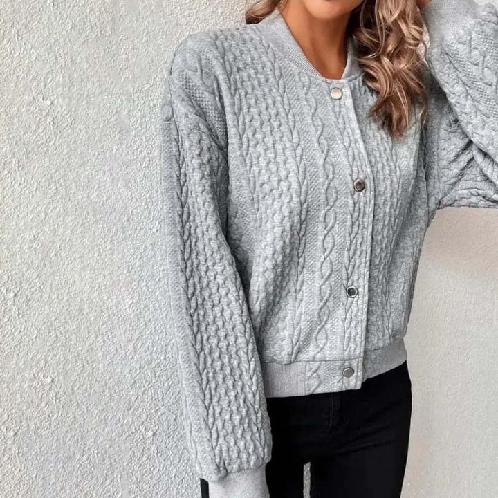 Grauer Strickpullover mit Zopfmuster, lange Ärmel, Knopfleiste, getragen von Frau. Modischer Damenpullover, gemütlich, stilvoll, Herbstmode.