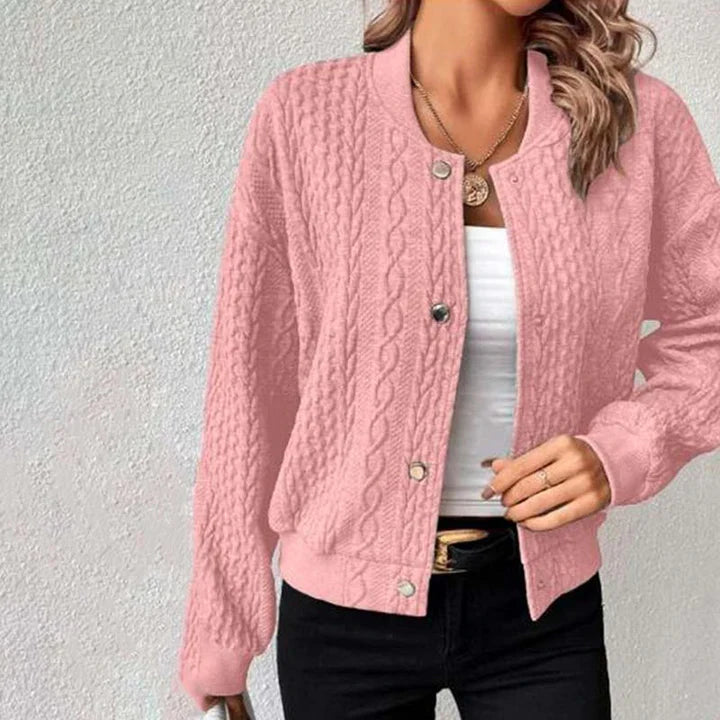 Damen rosa Strickjacke mit Zopfmuster, Knopfleiste und Rundhalsausschnitt, kombiniert mit weißem Top und schwarzer Hose. Modische Herbstbekleidung.