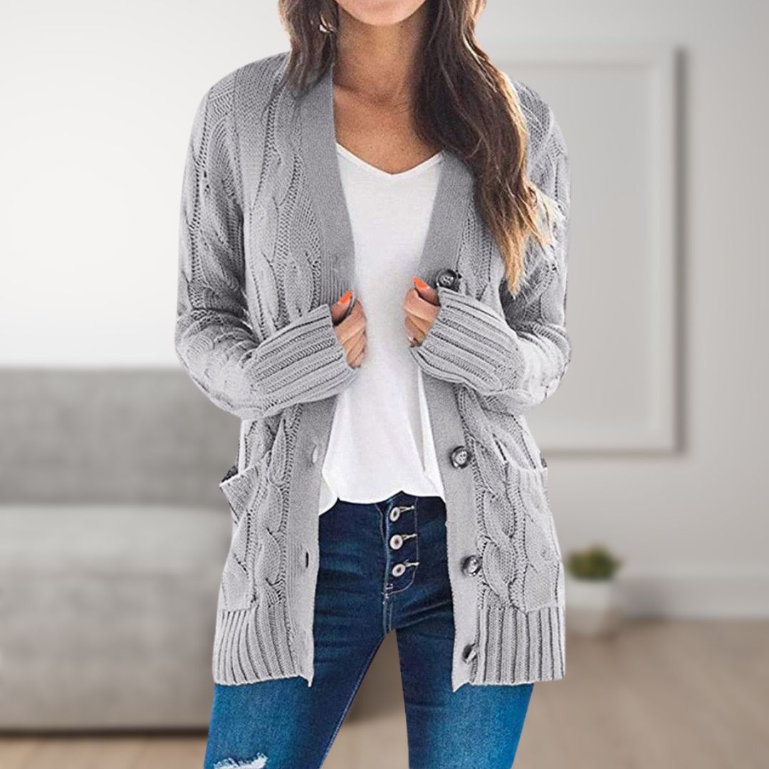 Frau trägt graue Strickjacke mit Zopfmuster, weiße Bluse und blaue Jeans. Modetrend, gemütlicher Look, Herbstmode, Damenbekleidung.