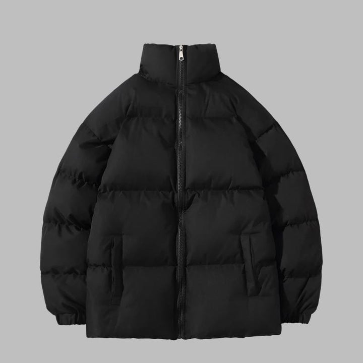 Schwarze Daunenjacke mit Reißverschluss, Stehkragen und Seitentaschen vor grauem Hintergrund. Wintermode, warme Outdoor-Bekleidung.