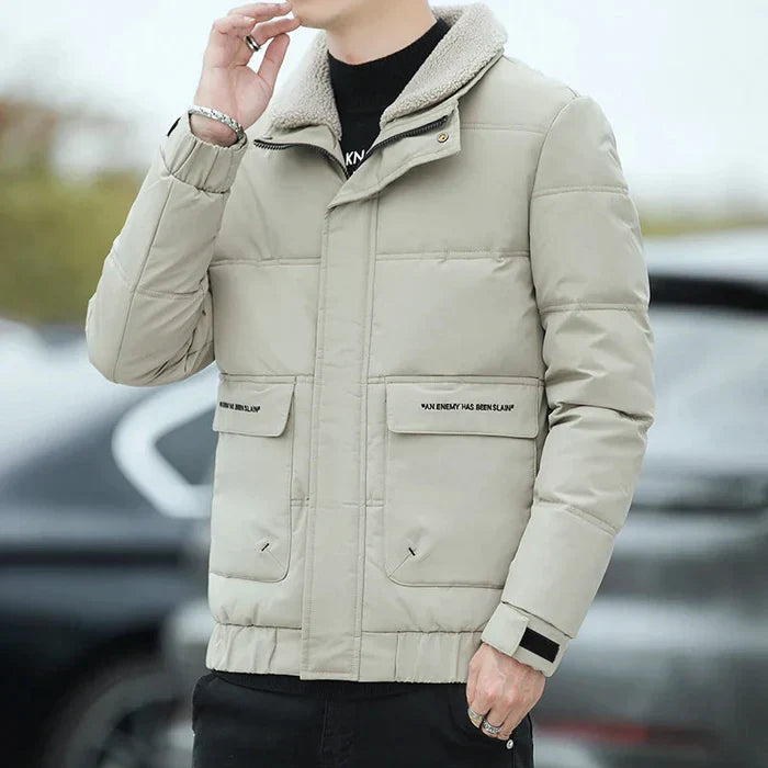 Ein Mann trägt eine beige Winterjacke mit Stehkragen und Taschen, ideal für kaltes Wetter. Modische Herrenbekleidung, warm und stilvoll.