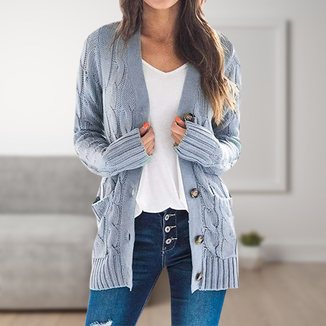 Frau trägt graue Strickjacke mit Zopfmuster, weiße Bluse und Jeans. Modetrend, gemütlicher Look, Herbstmode, Damenbekleidung, lässiger Stil.