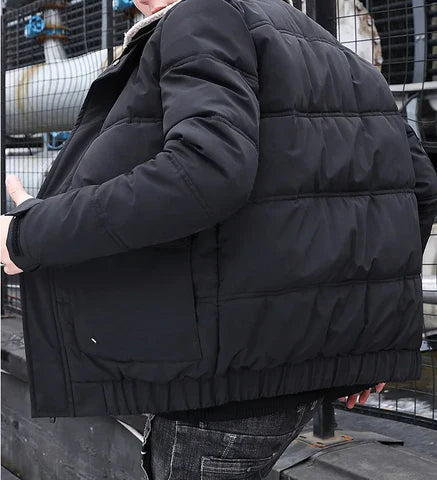 Mann in schwarzer, gesteppter Winterjacke auf urbanem Hintergrund. Modische, warme Jacke für kalte Temperaturen. Outdoor-Bekleidung.