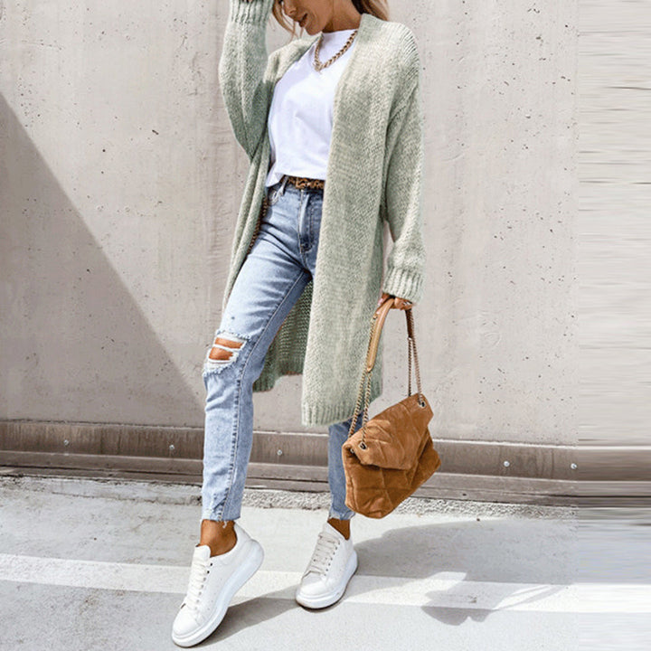 Dame in lässigem Outfit: Grüner Cardigan, weißes T-Shirt, zerrissene Jeans, weiße Sneaker, braune Handtasche. Modetrend, Streetstyle, Herbstmode.