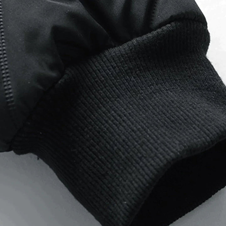 Schwarzer Ärmel einer Winterjacke mit geripptem Bündchen, Nahaufnahme. Hochwertige Outdoor-Bekleidung, warm und wetterfest.