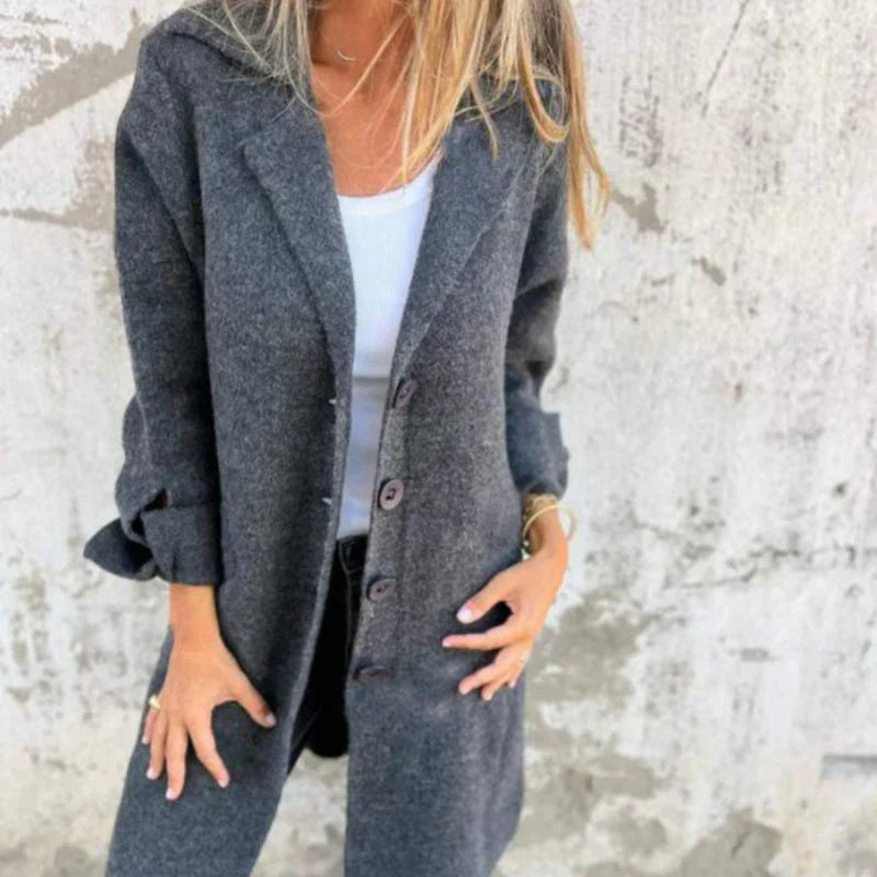Frau in grauem Wollmantel vor Betonwand, modischer Herbstlook, eleganter Damenmantel, lässiger Stil, warme Oberbekleidung, Streetwear-Trend.