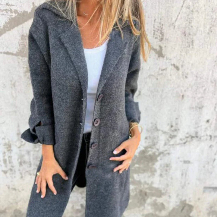 Frau in grauem Wollmantel vor Betonwand, modischer Herbstlook, eleganter Damenmantel, lässiger Stil, warme Oberbekleidung, Streetwear-Trend.