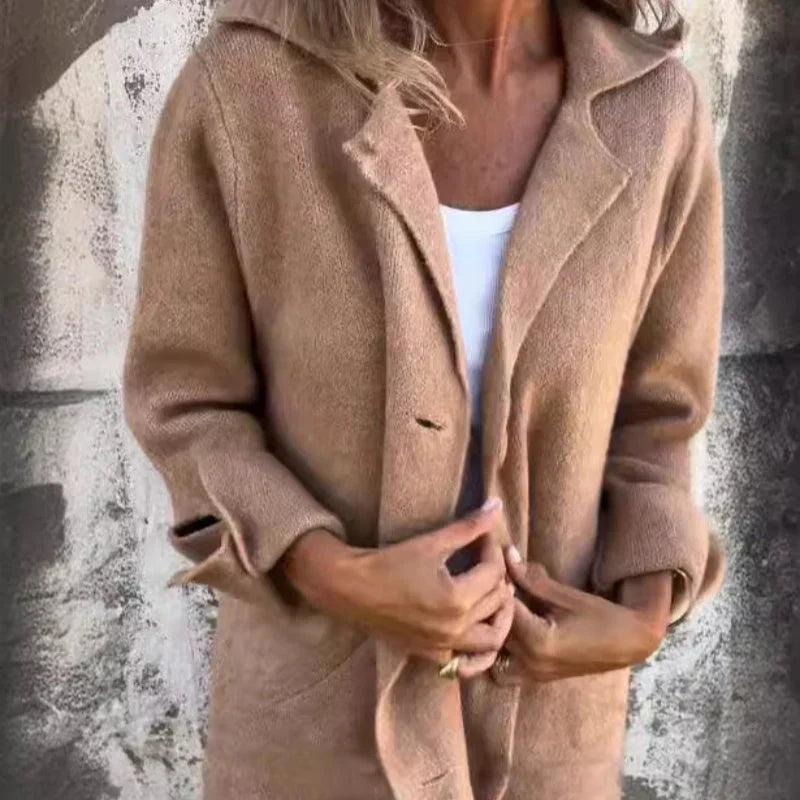 Dame in beigem Wollmantel vor Betonwand, modisch gekleidet, Herbstmode, eleganter Look, warme Oberbekleidung, stilvoller Mantel für kühle Tage.