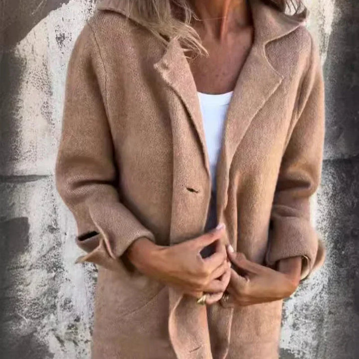 Dame in beigem Wollmantel vor Betonwand, modisch gekleidet, Herbstmode, eleganter Look, warme Oberbekleidung, stilvoller Mantel für kühle Tage.