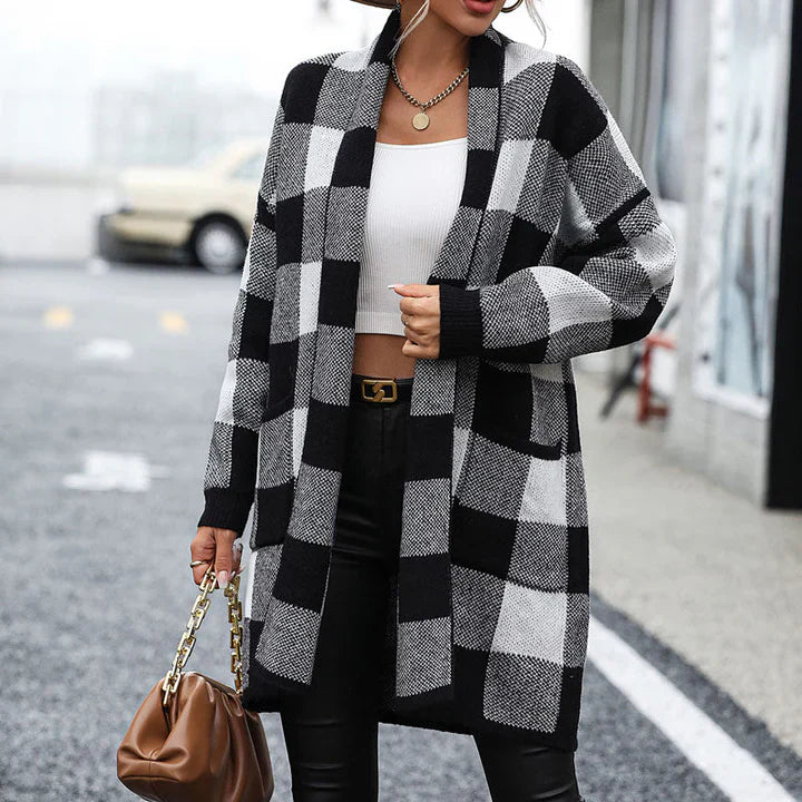 Frau trägt schwarz-weiß karierten Cardigan, weiße Bluse, schwarze Lederhose, braune Handtasche. Modetrend Herbst, stilvoller Streetstyle Look.