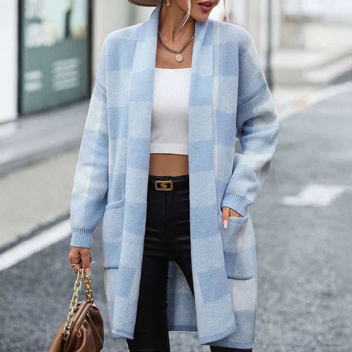 Frau in hellblauem Karo-Cardigan, weißem Crop-Top und schwarzer Hose auf Straße. Modetrend, Herbstmode, lässiger Stil, Damenbekleidung.