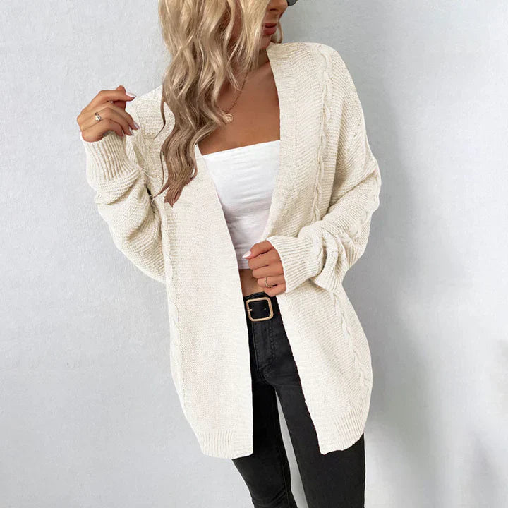Blonde Frau trägt weißen Strick-Cardigan, weißes Top und schwarze Jeans. Modetrend, lässiger Herbst-Look, Damenmode, gemütlicher Stil.