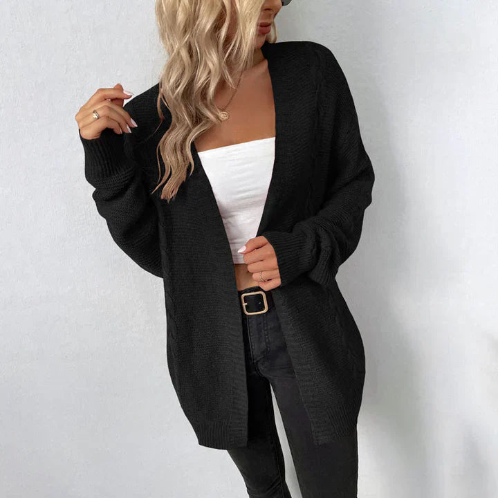 Blonde Frau trägt schwarzen Strick-Cardigan, weißes Top und schwarze Jeans. Modetrend, lässiger Look, Damenmode, Herbstoutfit.