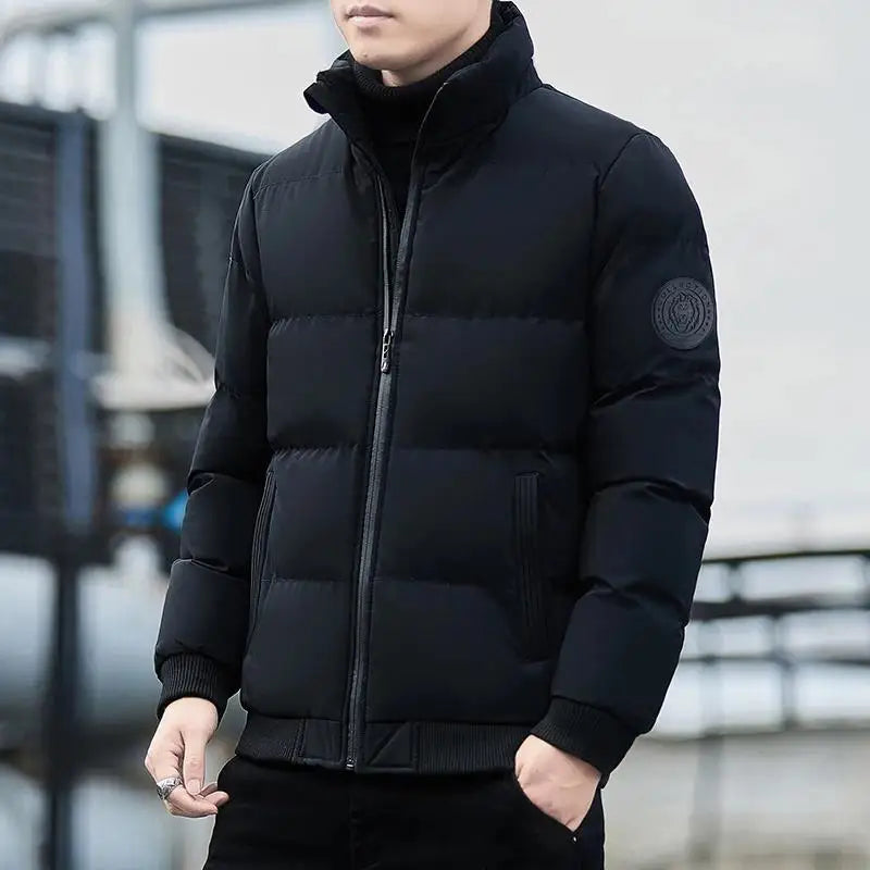 Mann in schwarzer Daunenjacke, Reißverschluss geschlossen, urbaner Hintergrund. Wintermode, warme Jacke, stilvoll, modern, Outdoor-Bekleidung.