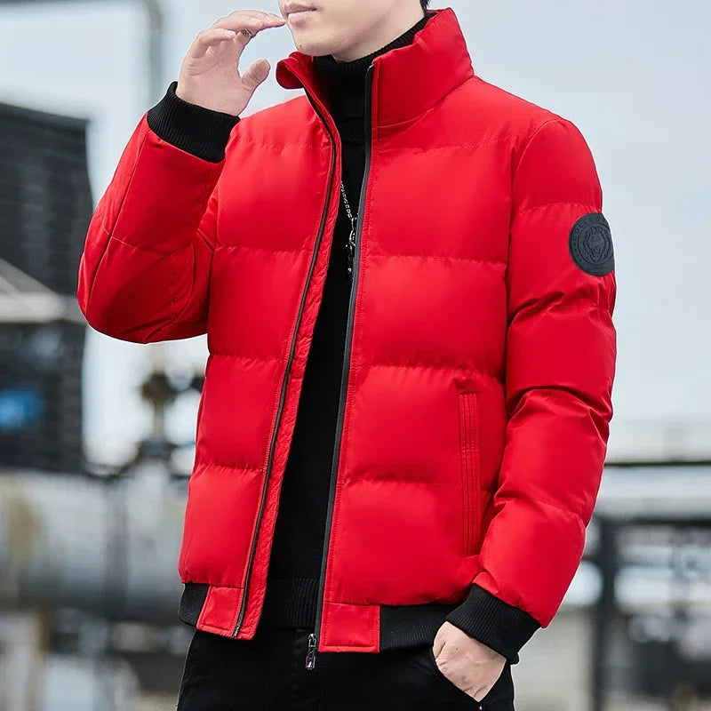 Mann in roter Daunenjacke, stehend im Freien. Modische Winterjacke, warm und stilvoll, ideal für kalte Temperaturen. Outdoor-Bekleidung, Herrenmode.