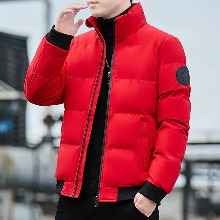 Mann in roter Daunenjacke, stehend im Freien. Modische Winterjacke, warm und stilvoll, ideal für kalte Temperaturen. Outdoor-Bekleidung, Herrenmode.