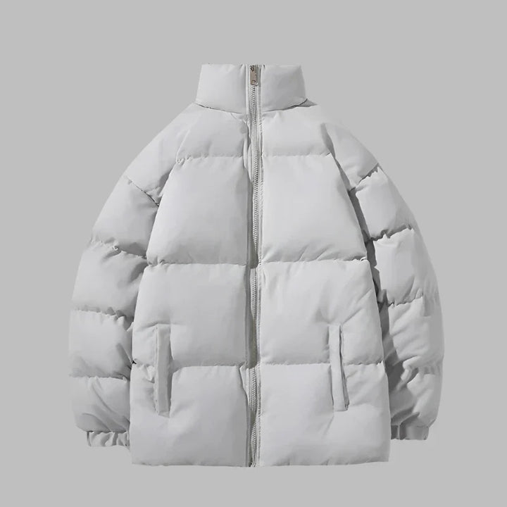 Graue Daunenjacke mit Reißverschluss, Stehkragen und Seitentaschen. Wintermode, warme Oberbekleidung, stilvolle Pufferjacke für kalte Tage.