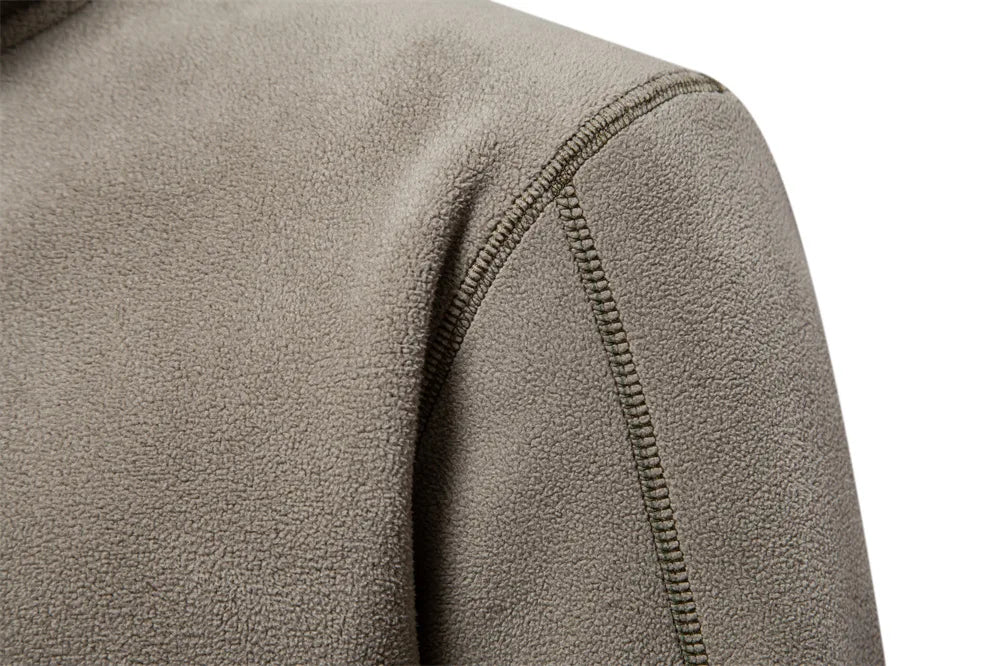Nahaufnahme einer olivgrünen Fleecejacke mit sichtbaren Nähten, weichem Stoff und strukturierter Oberfläche. Ideal für Outdoor-Aktivitäten und Herbstmode.