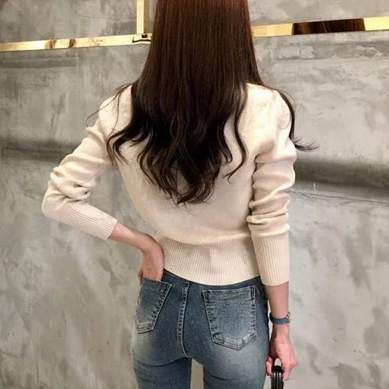 Frau in beigem Pullover und blauer Jeans von hinten, modernes Outfit, lässiger Stil, glattes braunes Haar, modische Kleidung, urbaner Hintergrund.
