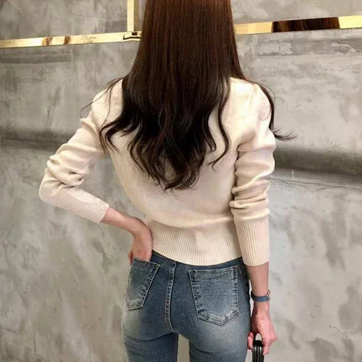 Frau in beigem Pullover und blauer Jeans von hinten, modernes Outfit, lässiger Stil, glattes braunes Haar, modische Kleidung, urbaner Hintergrund.