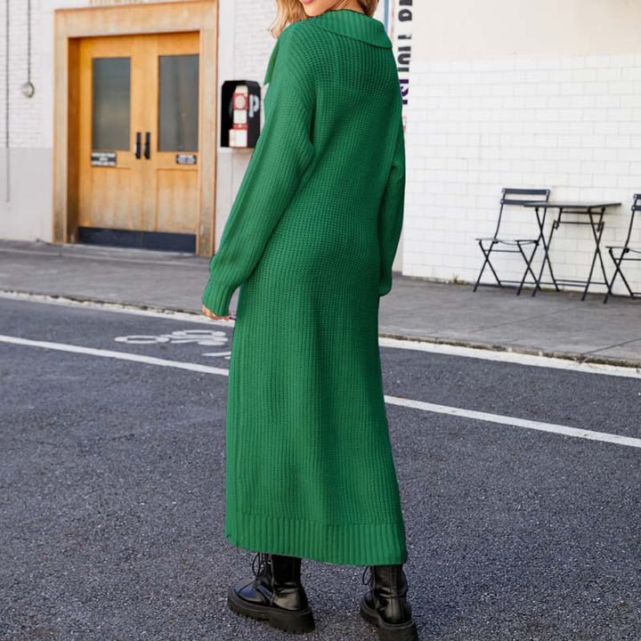 Frau in langem, grünem Strickkleid und schwarzen Stiefeln auf städtischer Straße. Modetrend Herbst, Streetstyle, urbaner Look.