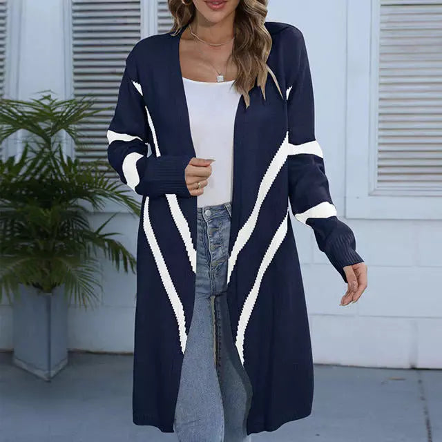 Dame in blau-weißem Strickmantel, weißem Top und Jeans vor Fensterläden. Modischer Cardigan, Herbstmode, lässiger Look.