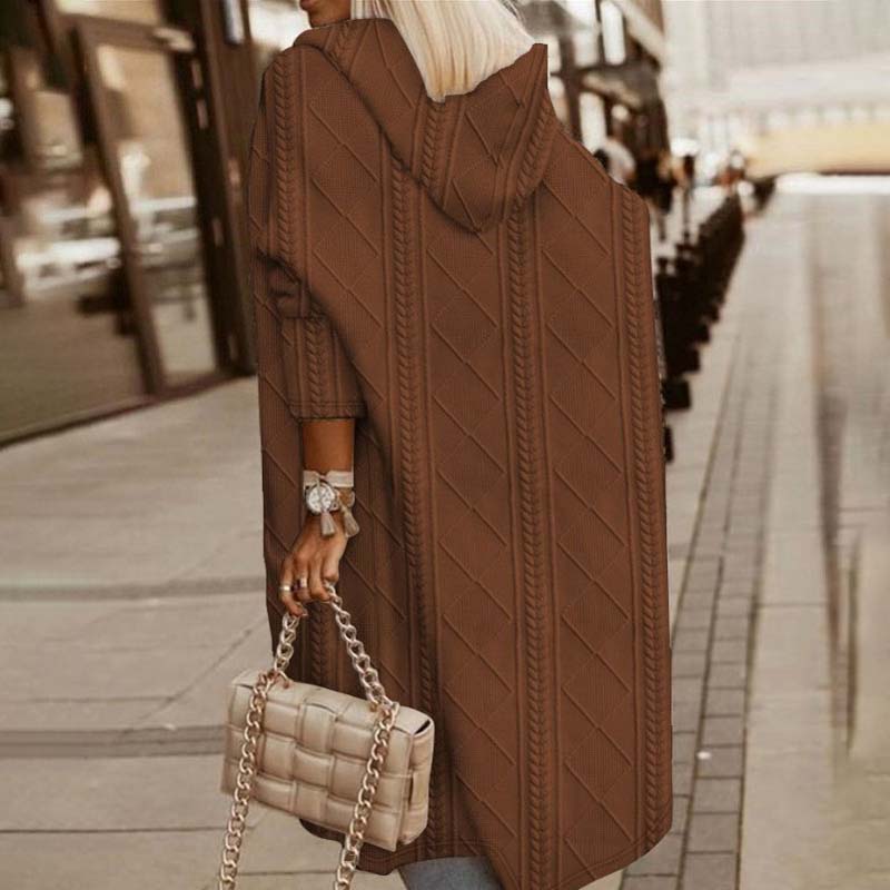 Frau in braunem Strickmantel mit Kapuze, hält gesteppte Handtasche. Modetrend Herbst, stilvolle Straßenmode, elegantes Design.