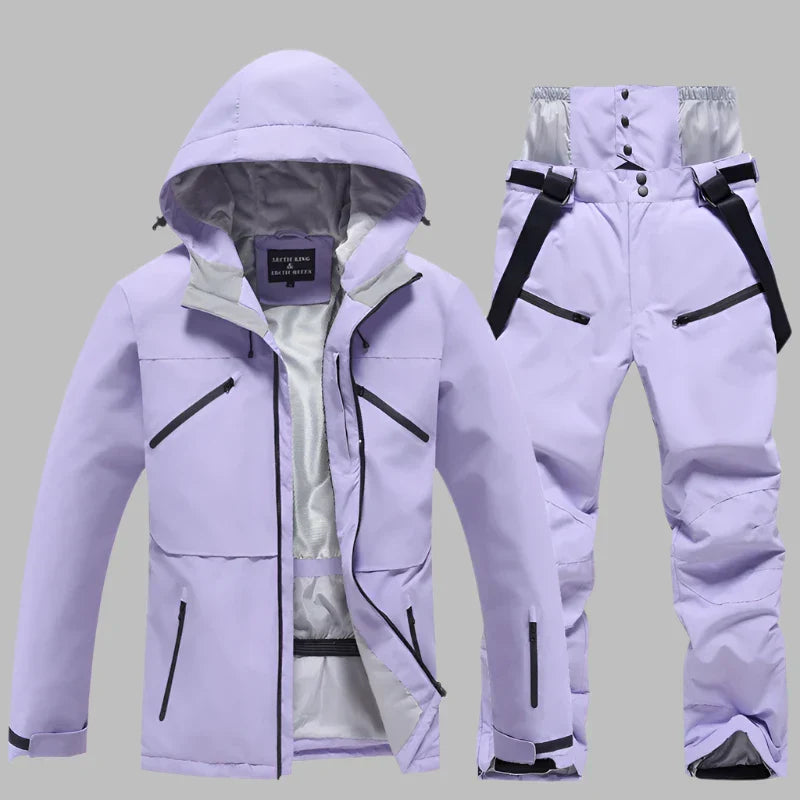 Lila Skianzug für Damen, bestehend aus wasserdichter Jacke mit Kapuze und passender Hose, ideal für Wintersport und Outdoor-Aktivitäten.