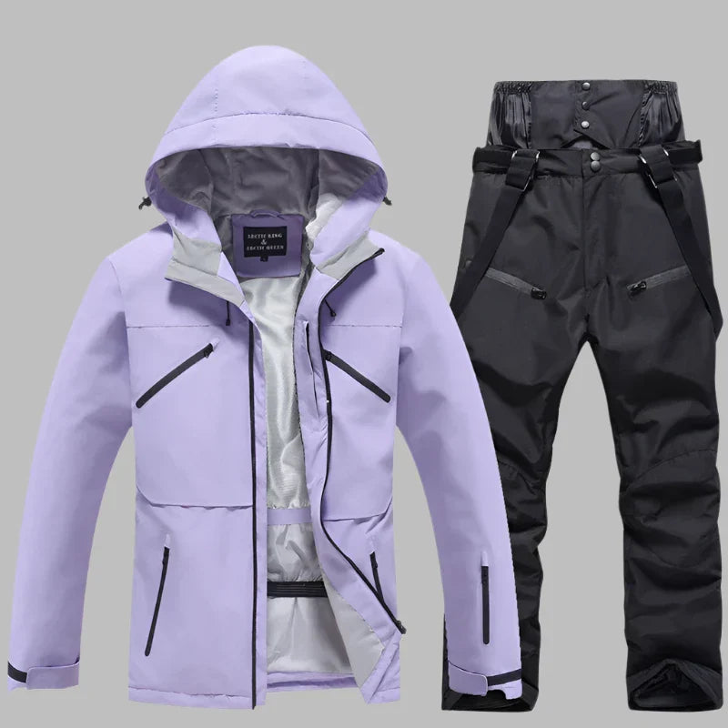 Lila Skijacke mit Kapuze und schwarze Skihose mit Hosenträgern auf grauem Hintergrund. Winterbekleidung, Outdoor, wasserdicht, atmungsaktiv.