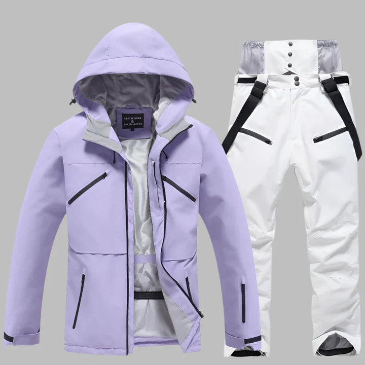 Lila Skijacke mit Kapuze und weiße Skihose mit Hosenträgern auf grauem Hintergrund. Winterbekleidung, Outdoor, wasserdicht, atmungsaktiv.
