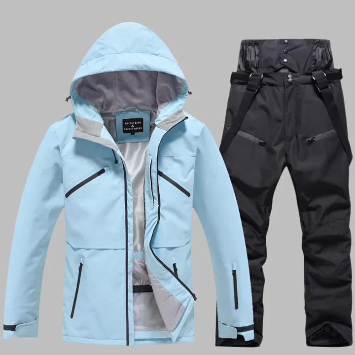 Hellblaue Outdoor-Jacke mit Kapuze und schwarze wasserdichte Hose. Ideal für Skifahren und Wandern. Funktionale Taschen, atmungsaktiv und winddicht.