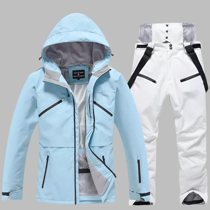 Hellblaue Skijacke mit Kapuze und weiße Skihose mit Hosenträgern auf grauem Hintergrund. Winterbekleidung, Outdoor, Skimode, wasserdicht.