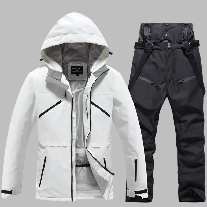 Weiße Skijacke mit Kapuze und schwarze Skihose mit Hosenträgern auf grauem Hintergrund. Winterbekleidung, Outdoor, wasserdicht, atmungsaktiv.
