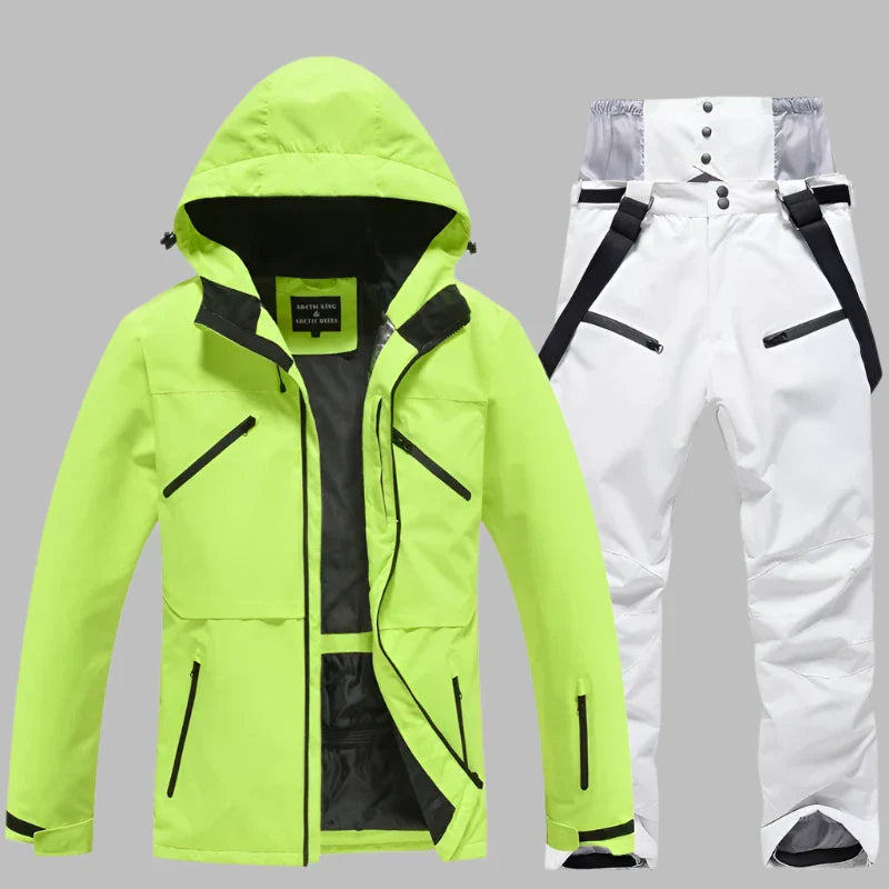 Neongelbe Skijacke mit Kapuze und weiße Skihose mit Hosenträgern auf grauem Hintergrund. Wasserdicht, atmungsaktiv, Winterbekleidung.