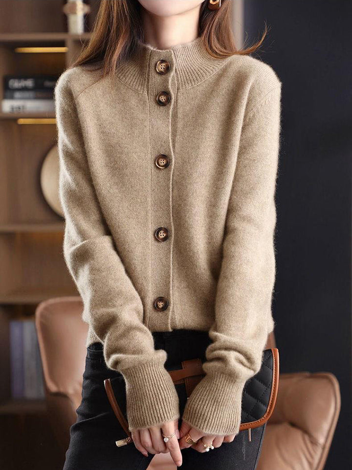Frau trägt beige Strickjacke mit Holzknöpfen, modisch kombiniert mit schwarzer Hose. Elegante Herbstmode, gemütlicher Strick, stilvoller Look.