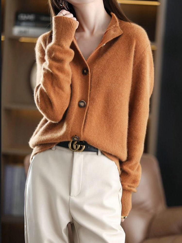 Frau trägt braunen Strickpullover und weiße Hose, modisch kombiniert mit schwarzem Gürtel. Eleganter Herbstlook, stilvolle Damenmode.