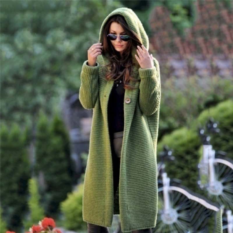 Grüne Strickjacke mit Kapuze, getragen von Frau im Freien. Modetrend, Herbstmode, stilvolle Damenbekleidung, lässiger Look, Outdoor-Mode.