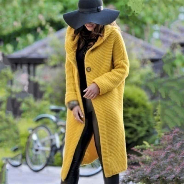 Frau in gelbem Strickmantel und schwarzem Hut spaziert im Park. Herbstmode, stilvoll, elegant, Outdoor, Damenbekleidung, Trend 2023.